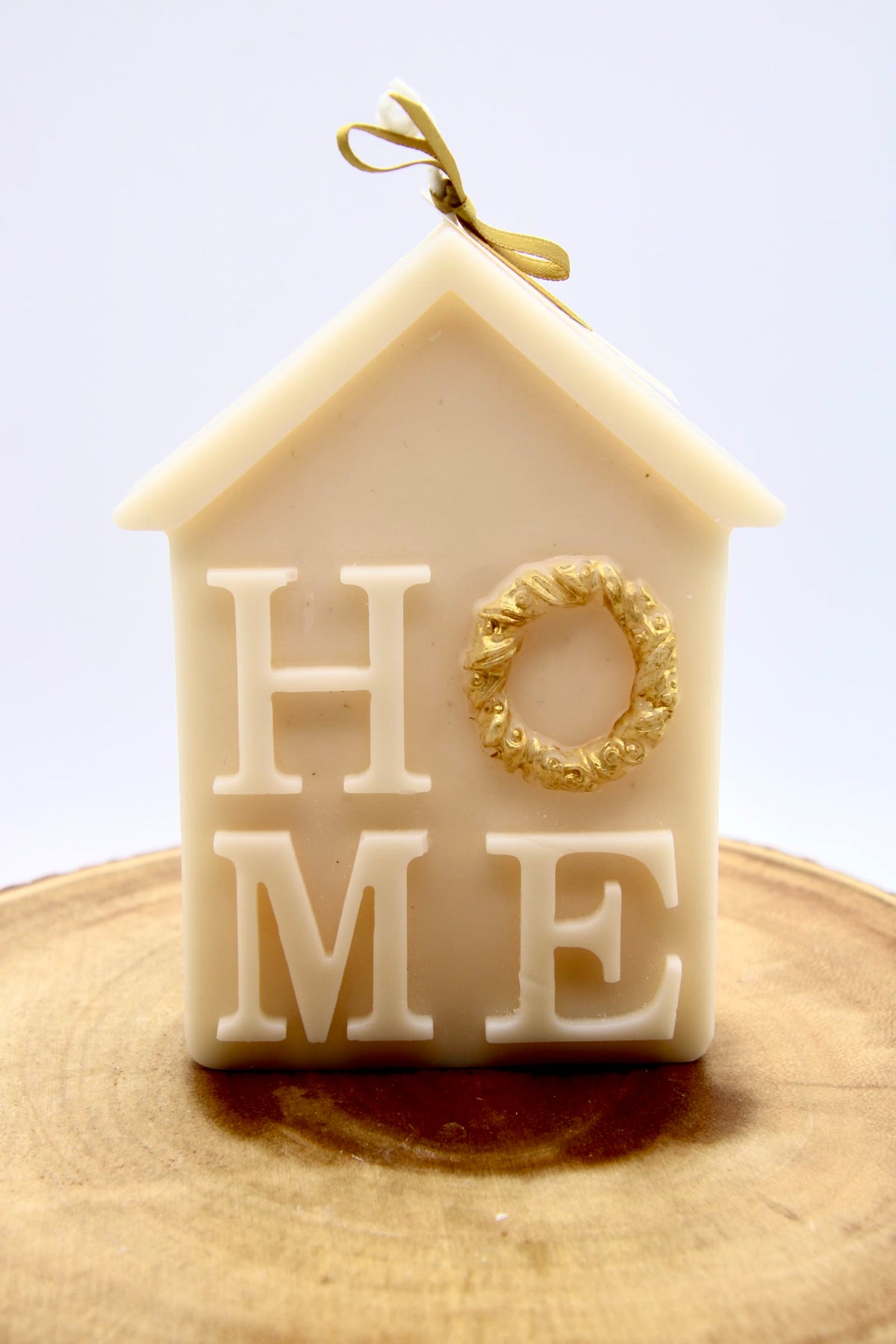 Ivory house-shaped Christmas candle that spells HOME, with a gold wreath as the O
