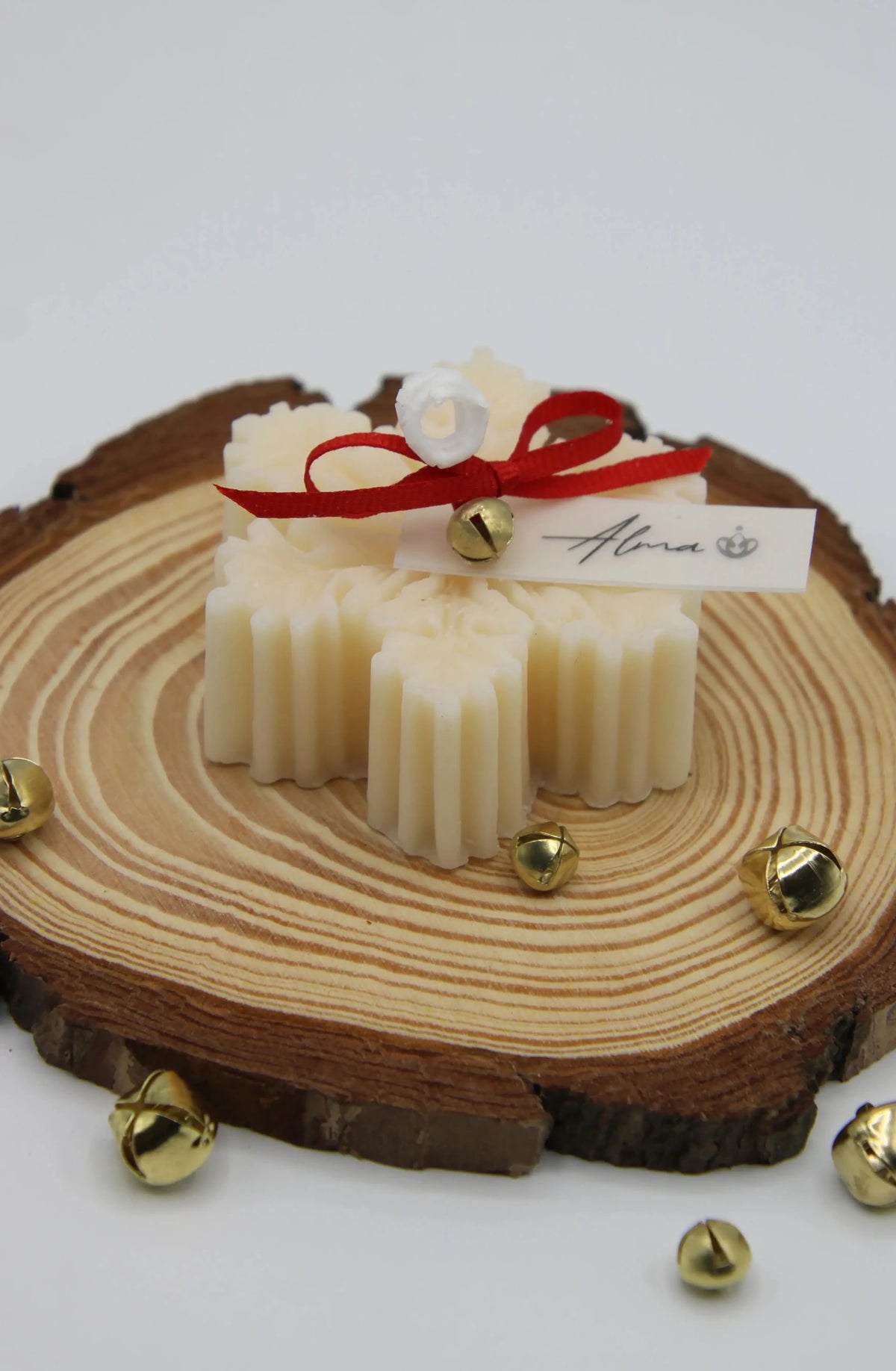 Ivory snowflake Christmas candle tied with a red ribbon on a wood slice, Alma Gift