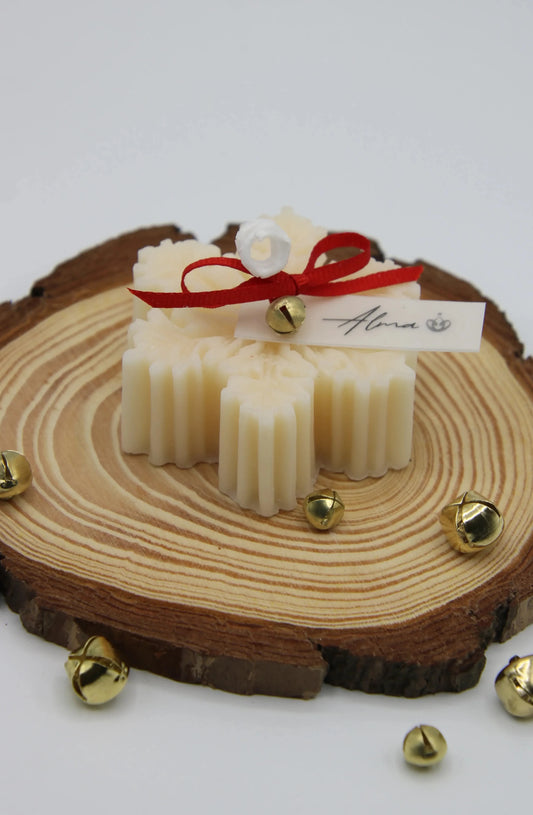 Ivory snowflake Christmas candle tied with a red ribbon on a wood slice, Alma Gift