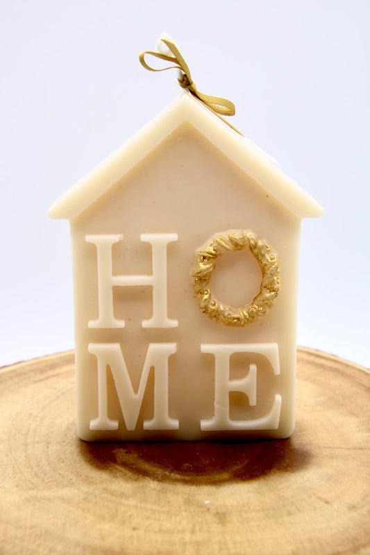 Ivory house-shaped Christmas candle that spells HOME, with a gold wreath as the O