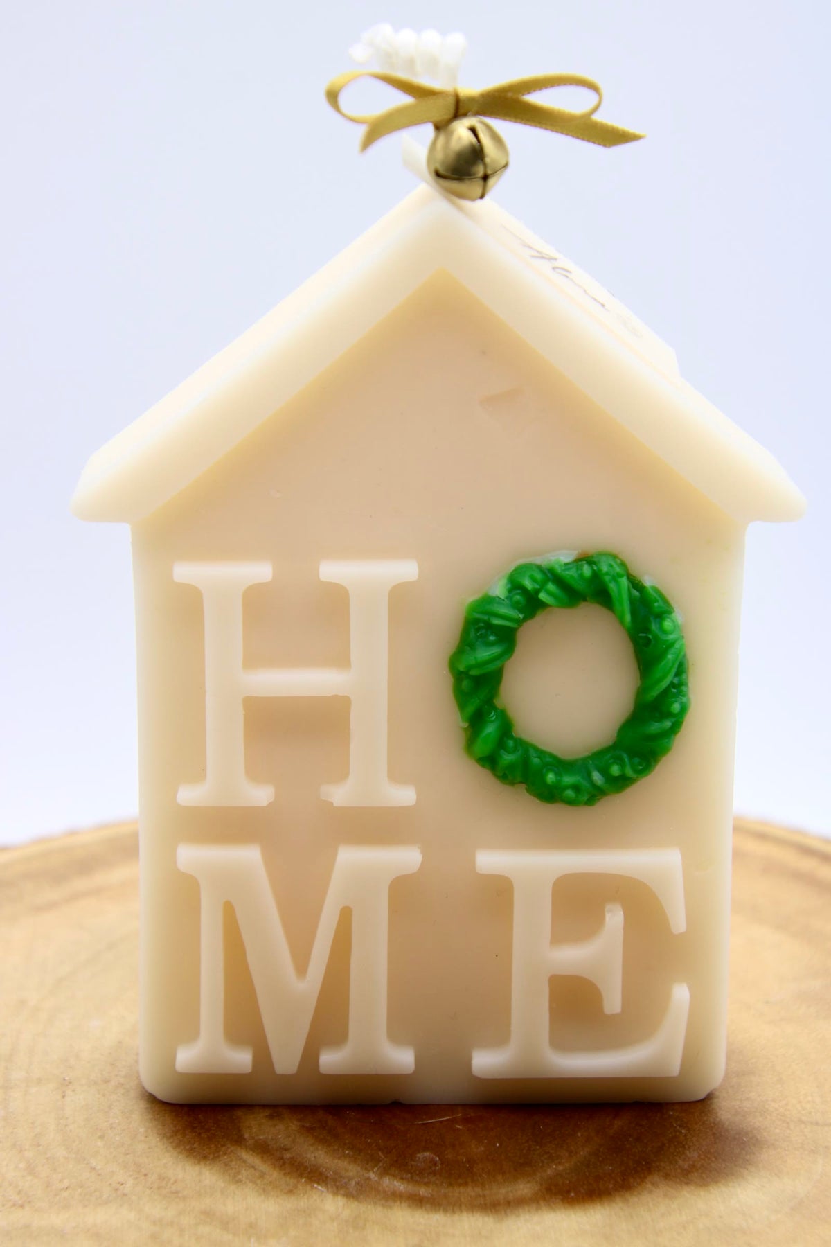 Ivory house-shaped Christmas candle that spells HOME, with a green wreath as the O